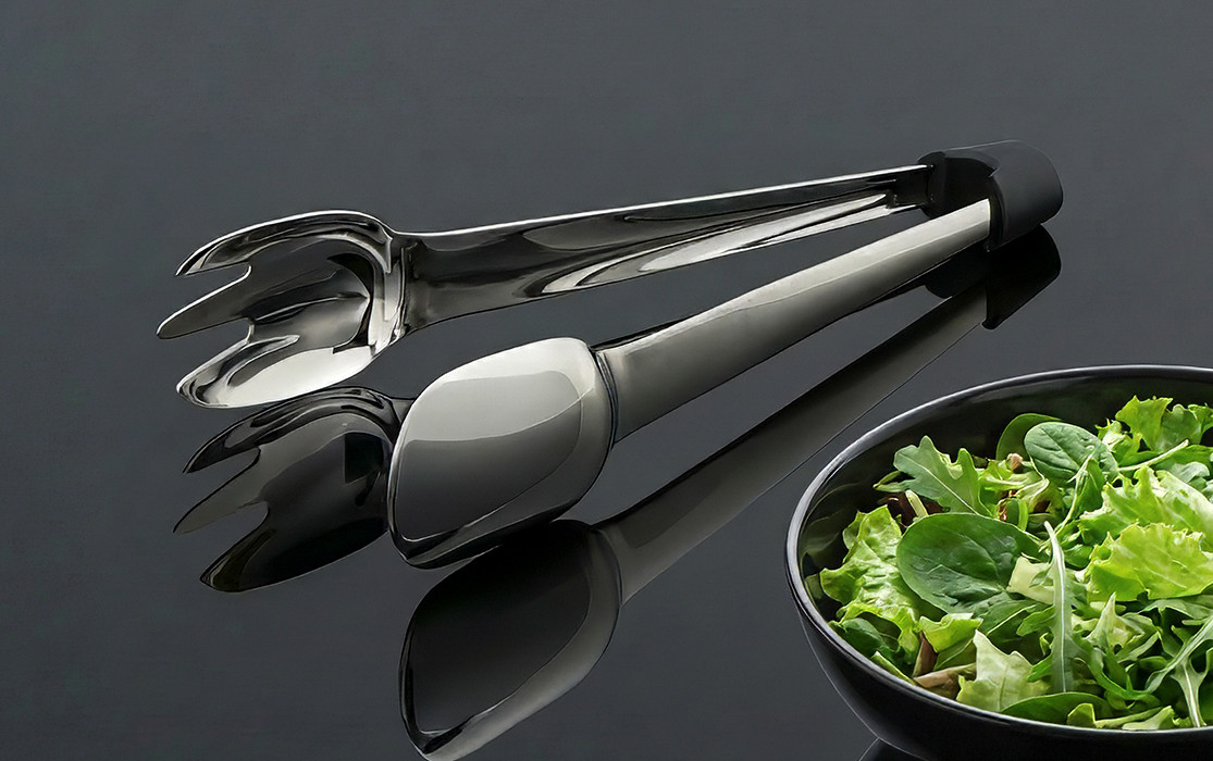 RE98-CUTLA SALAD stainless steel salad servers next to a bowl of fresh salad on a black surface