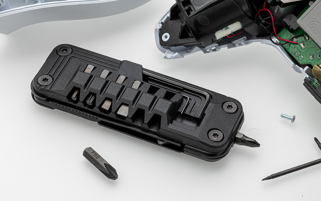 RE98-PINNO multitool with various bits, lying on a white surface next to electronic parts