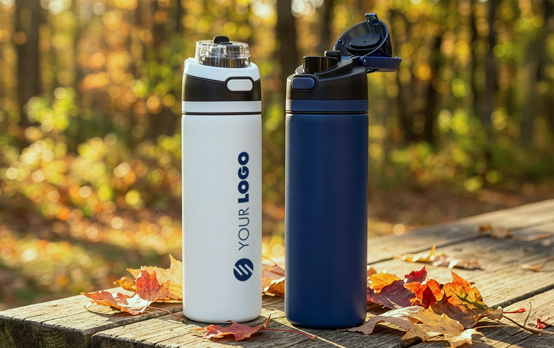 Two RETUMBLER-URBIX thermal bottles, one white with a logo and one blue, standing on a wooden table in an autumn forest